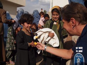 Naissotilas tervehtimässä afganistanilaisia lapsia ja naisia.